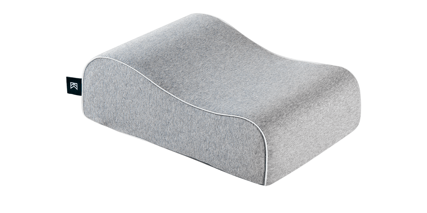 Keetsa Siesta pillow in heather gray, three-quarter view showing contoured ergonomic wave shape with white piping trim, soft jersey knit cover, and branded Keetsa tag.