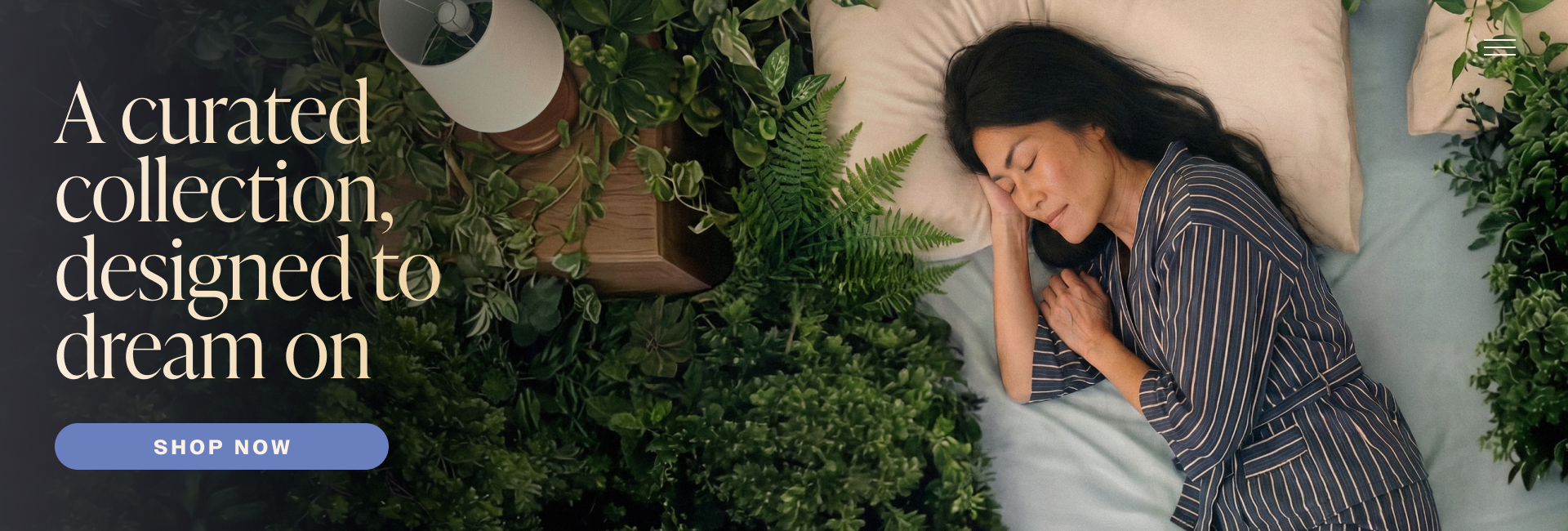 Keetsa homepage hero banner with overhead view of woman in striped pajamas sleeping peacefully on bed surrounded by lush greenery, ferns, and a nightstand lamp. Headline reads 'A curated collection, designed to dream on' with Shop Now button.