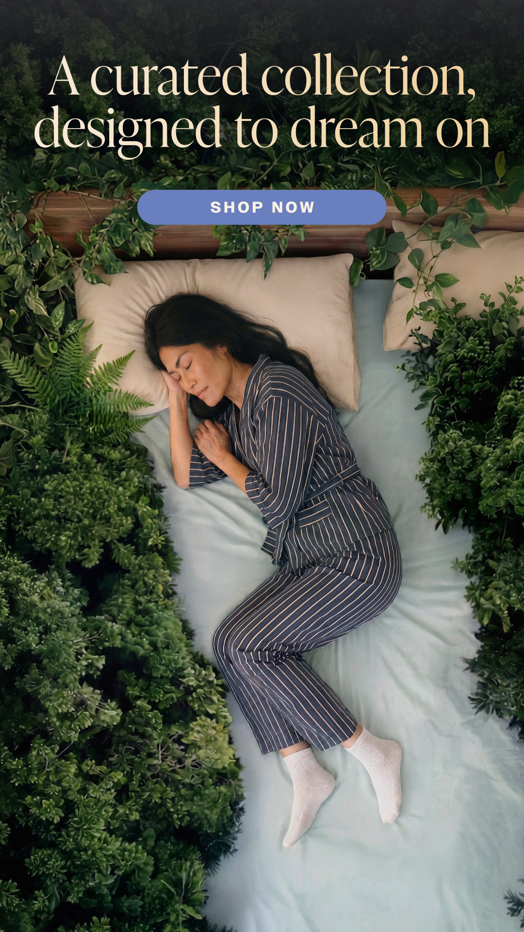 Keetsa mobile homepage hero showing aerial view of woman in striped pajamas curled up asleep on bed flanked by dense greenery and ferns. Headline 'A curated collection, designed to dream on' with Shop Now call to action.