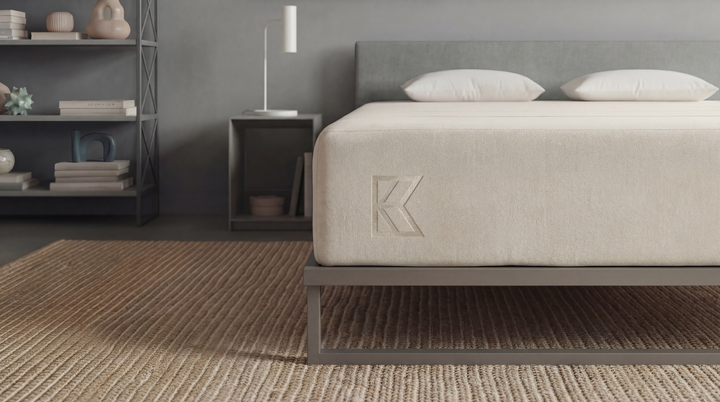 Detailed side view of Keetsa Cloud mattress with smooth fabric cover and subtle K logo on a metal frame, highlighting consistent edge support, refined construction, and a low-profile base suited for modern bedroom styling.