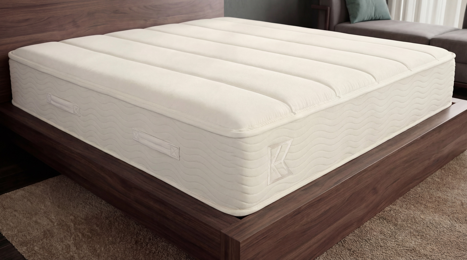 Close-up of Keetsa Plus mattress corner on a walnut platform bed, featuring a cream quilted cover with wave stitching, reinforced edges, and built-in side handles, highlighting durable construction and consistent support across the surface.