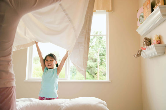 Girl helping replace non-toxic bedding and mattress protector on bed