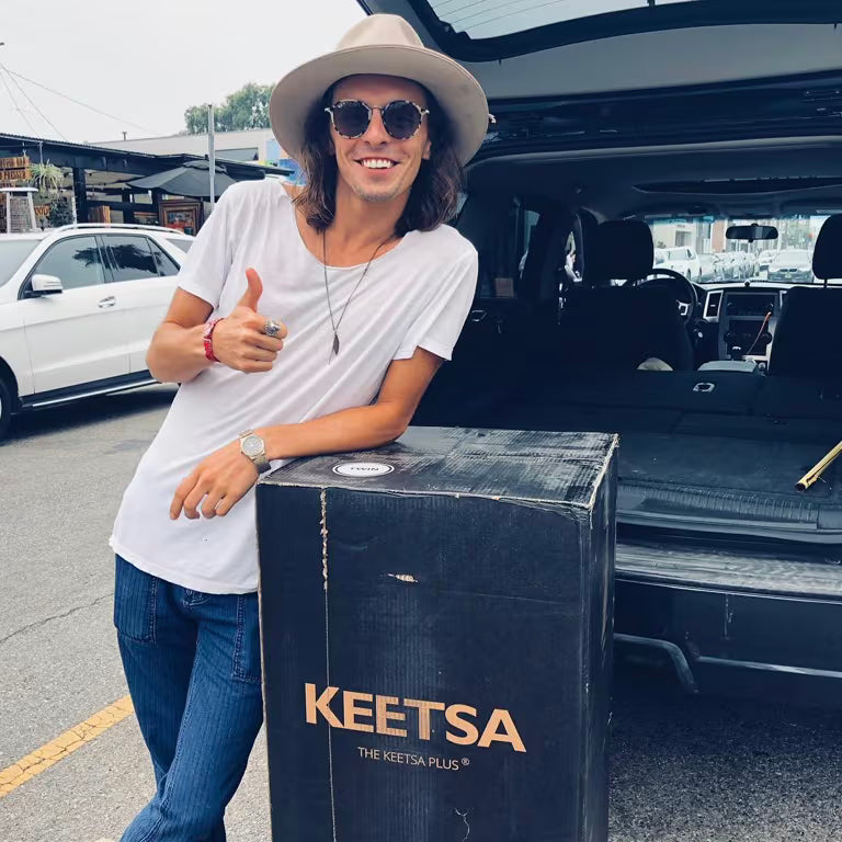 Customer giving a thumbs up next to his Keetsa Plus mattress box beside an open car