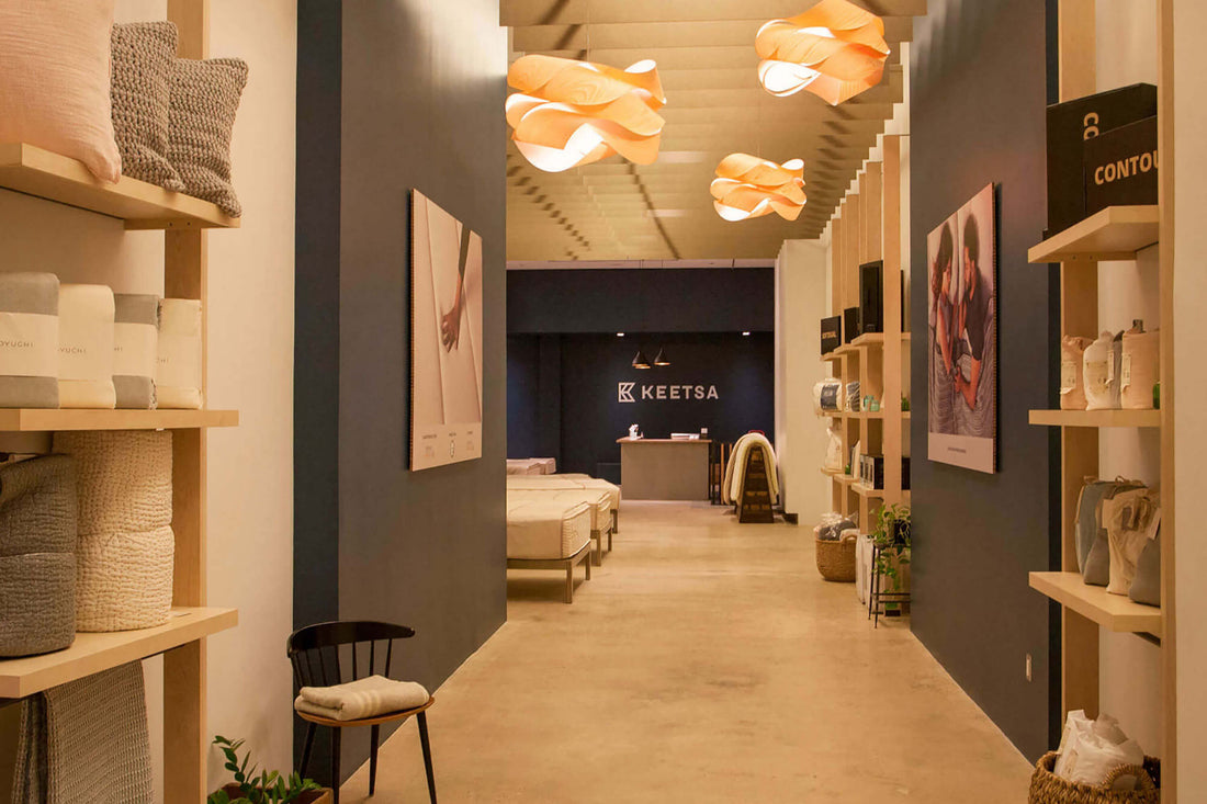 Keetsa SoHo showroom interior in Manhattan featuring displays of bed-in-a-box mattresses, pillows, and bedding accessories arranged across the retail floor, showcasing the full product collection in a bright modern shopping environment open to walk-in customers.
