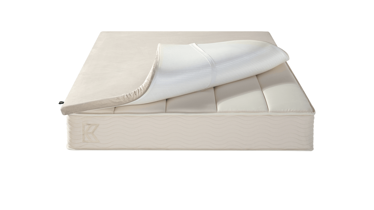 Keetsa Basic Comfort Layer mattress topper partially lifted to reveal elastic corner straps, highlighting its secure fit design that helps keep the topper in place while adding an extra layer of cushioning comfort.