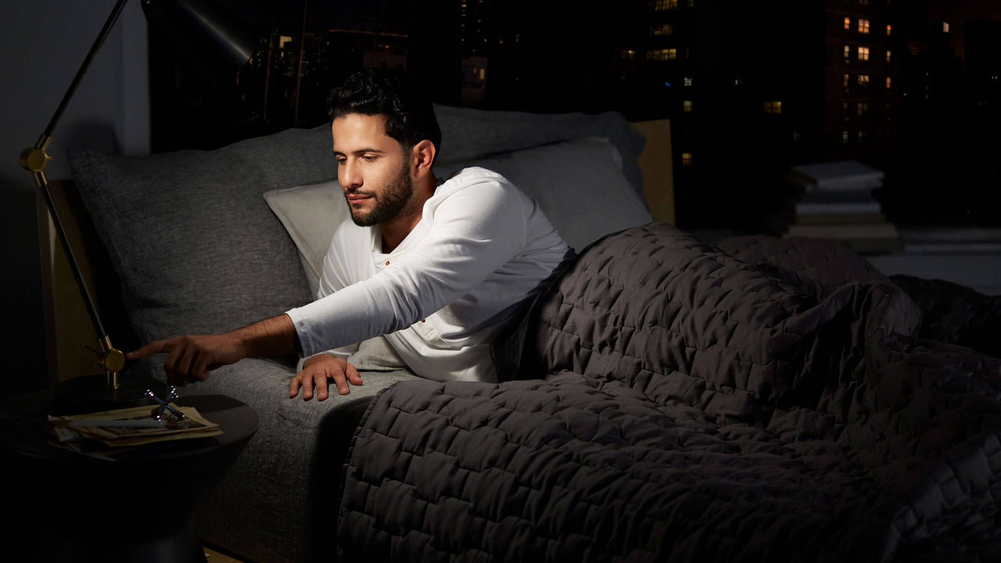 Keetsa Cloud mattress shown in a nighttime bedroom setting as a man reaches to turn off a bedside lamp, highlighting the mattress’s plush comfort and supportive design for restful sleep.