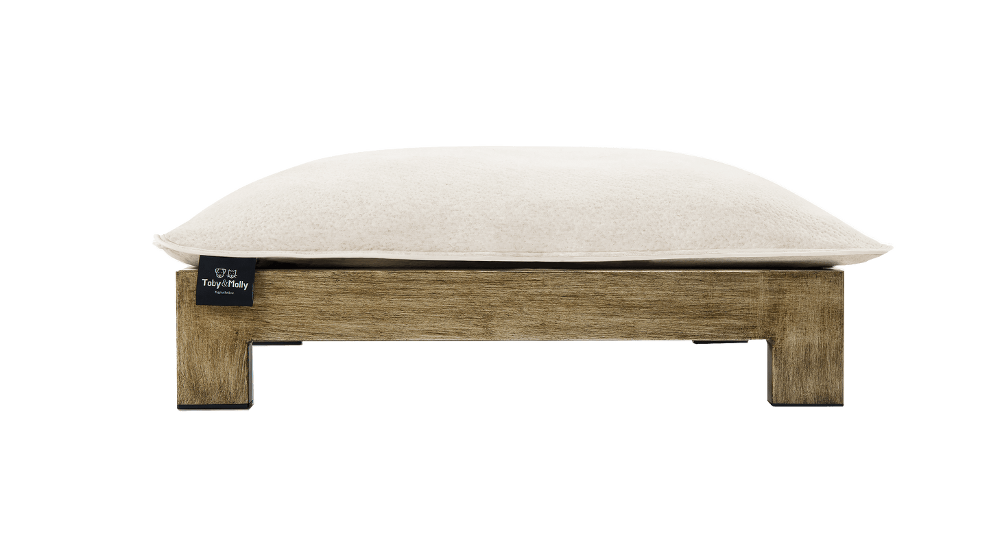 Zinus Toby & Molly pet bed front view showing thick cream cushion with branded tag on elevated rustic wood platform frame with square legs for airflow underneath.